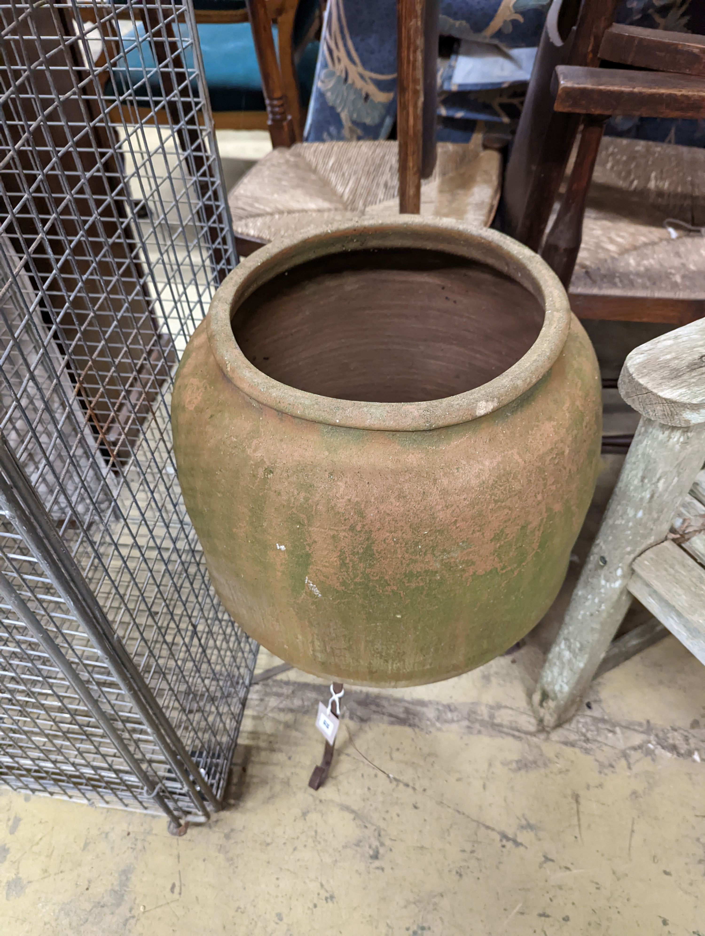 A terracotta garden urn on wrought iron stand. W-38cm, D-38cm, H-68cm.